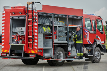 A firefighter meticulously prepares a modern firetruck for a mission to evacuate and respond to...