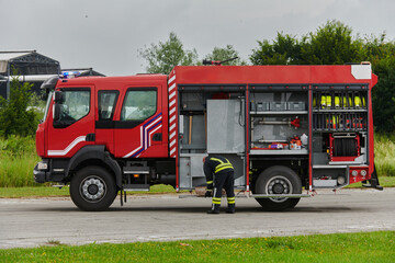A firefighter meticulously prepares a modern firetruck for a mission to evacuate and respond to...