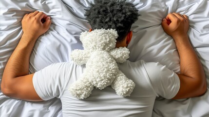 Young man sleeping in bed with a teddy bear on his shoulders.
