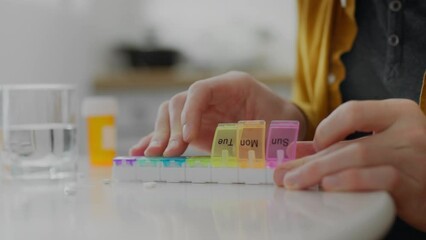 During the course of treatment, the young man systematically takes prescribed medications for seven days. Pills measured for each day, a man's hand takes out pills from a medicine organizer