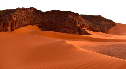Fototapeta na wymiar Sahara desert, orange dunes. Holidays and travel in Algeria, morning light over the desert. Rocks in the background. Fine lines of sand dunes.