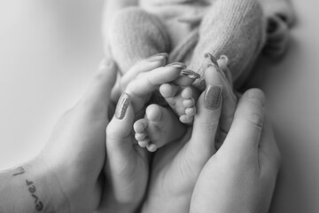 baby's feet in the hands of the older child and mom black and white photo