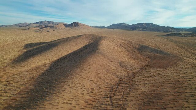 Aerial view of rolling desert hills and creosote under a soft blue sky