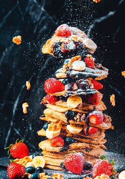 Pancakes stacked with strawberries, bananas, nuts, blueberries, chocolate, food photography