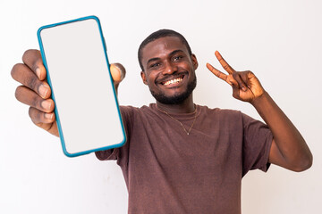 Portrait of excited black African american guy holding big smartphone with white blank screen in...