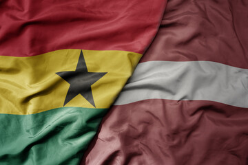 Fototapeta premium big waving national colorful flag of latvia and national flag of ghana .