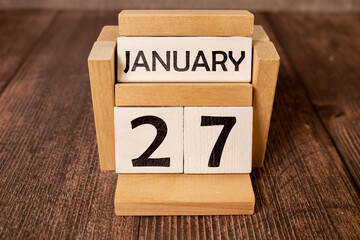 Vintage photo, January 27th. Date of 27 January on wooden cube calendar, copy space for text on board
