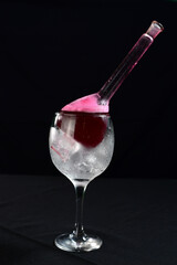 refreshing alcoholic drink with berries, ice vodka and gin, lemon peel served in glass cup on the counter on blurred background