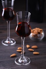 Liqueur glasses with tasty amaretto and almonds on wooden table, closeup