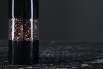 Pepper shaker on dark marble table, closeup. Space for text