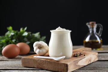 Fresh mayonnaise sauce in glass jar and ingredients on wooden table