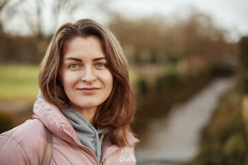Young beautiful pretty tourist girl in warm hat and coat with backpack walking at cold autumn in Europe city enjoying her travel in Bietigheim-Bissingen, Deutschland. Outdoor portrait of young tourist