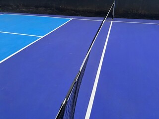 Pickle ball court in blue and white colors with net in black and white. Wide view of a pickleball...