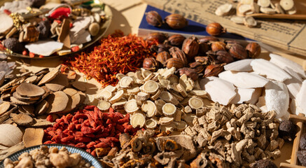 Ancient Chinese medicine and different herbal ingredients on table.