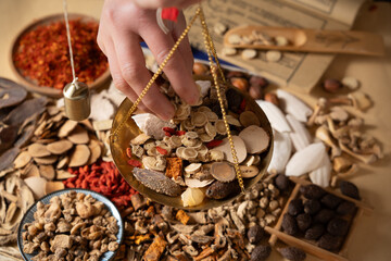 Ancient Chinese medicine and different herbal ingredients on table.