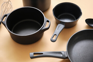 Cooking pots and frying pan on beige background, closeup