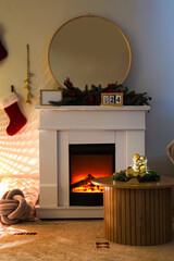 Fireplace with Christmas decorations and glowing lamp in dark living room