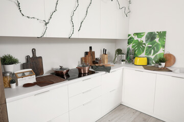 Interior of modern kitchen with white counters and utensils