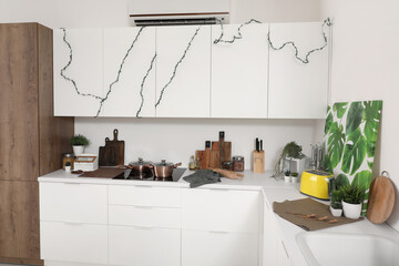 Interior of modern kitchen with white counters and utensils