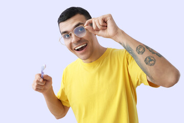 Handsome young man with healthy teeth and brush on purple background. Dental care concept