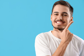 Handsome young man with healthy teeth on blue background. Dental care concept