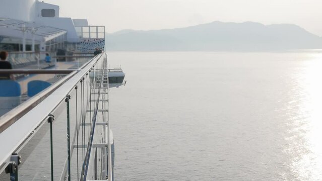 view on the top deck of the giant luxuary cruise ship from the aft area to forward with bridge view while slowly sailing into the bay in morning sunrise time.