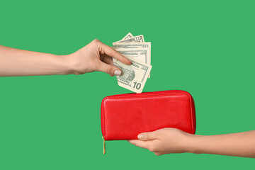 Female hands with wallet and money on green background
