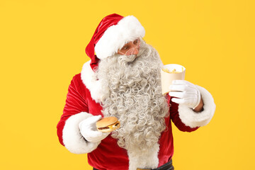 Shocked Santa Claus with tasty burger and french fries on yellow background