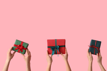 Female hands holding Christmas gift boxes on pink background