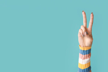 Young woman showing peace sign on blue background