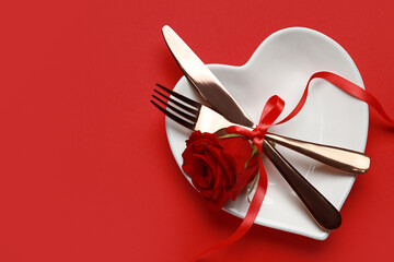 Table setting for Valentine's Day with rose on red background