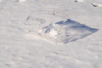 Icicle lies on white snow. The texture of snow and frozen ice. Close-up, copy space, space for text
