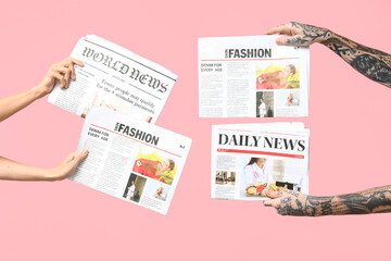 Female and male hands with newspapers on pink background