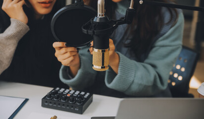 Woman recording a podcast on her laptop computer with headphones and a microscope. Female podcaster making audio podcast from her home studio.