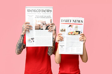 Couple with newspapers on pink background