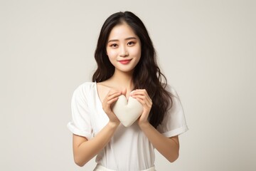 A woman holding a heart shaped pillow in her hands