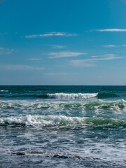 small waves on the beach with a bright blue sky
