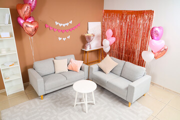 Interior of festive living room with grey sofas and paper heart garland. Valentine's Day celebration