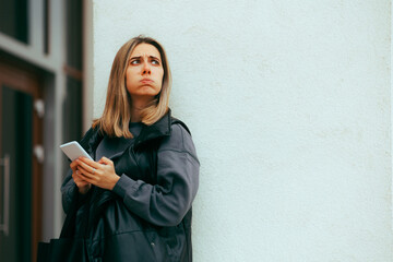 Woman Looking Outside Checking the Weather and her Phone. Bored annoyed girl waiting for her boyfriend on a date 
