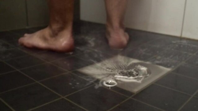 Slightly defocused background: Soapy water in shower drain, man's feet