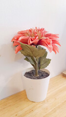 Artificial zinnias decorate a wooden table in a cafe.