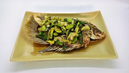 Ikan Gurame Goreng or fried freshwater fish with chilli sauce and vegetable. Serving on plate. Indonesian food and cuisine. Delicious Fried Gouramy, Selected Focus.