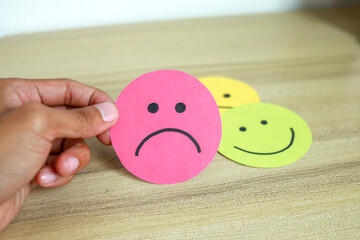 Dissapointed client choose sad face emoticon paper cut. Negative review, low rating and bad services
