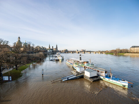 DRESDEN, GERMANY - 27. December 2023: Elbe river flood in the old town. The high water level is lifting the steam ships. The street is closed for traffic and measures have been made to prevent damage.