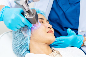 Asian Doctor doing laser on the woman face at beauty clinic. Beautiful woman having facial skin care treatment at beauty clinic, Facial skin care, anti-aging facial rejuvenation.