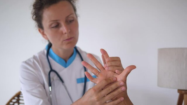 Female doctor examines of patient hand. Female doctor carefully examines deformed fingers of patient. Concept: doctors in hospital will definitely provide assistance to everyone who needs it.