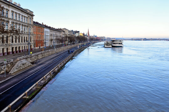 Budapest, Hungary - 12. 26. 2023. Aerial view of the flooding Danube river from the Chain bridge. high water level reaching the quay and asphalt low road closed to car traffic. pedestrians strolling