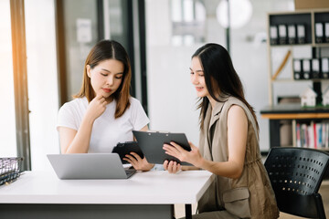 Two business workers talking on the smartphone and using laptop at the office..