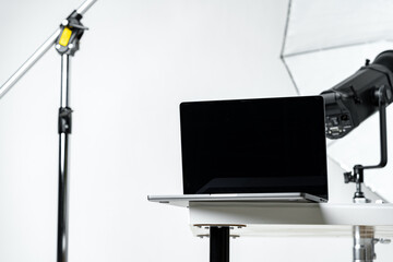 Laptop with black screen and photography equipment in photostudio