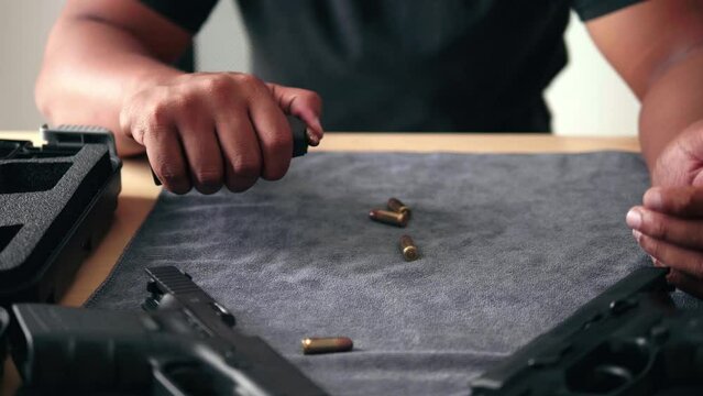Care and maintenance Bullet reloading and cleaning by an Asian man Disassembly of a firearm for cleaning and handheld gun safety inspection. Gun assembly. Weapon care. High quality 4k images.
